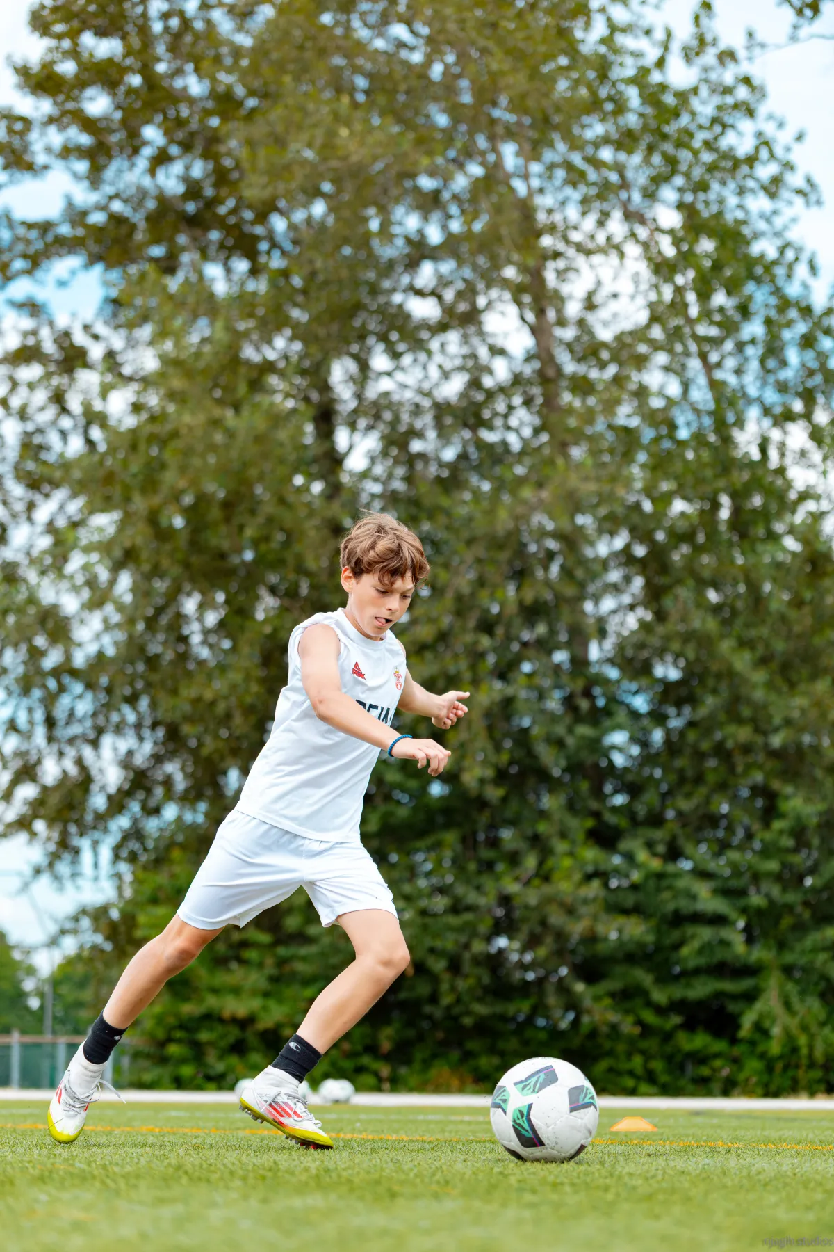 Boy kicking soccer ball on grass field during youth match - Follow Njagih Studios on Instagram