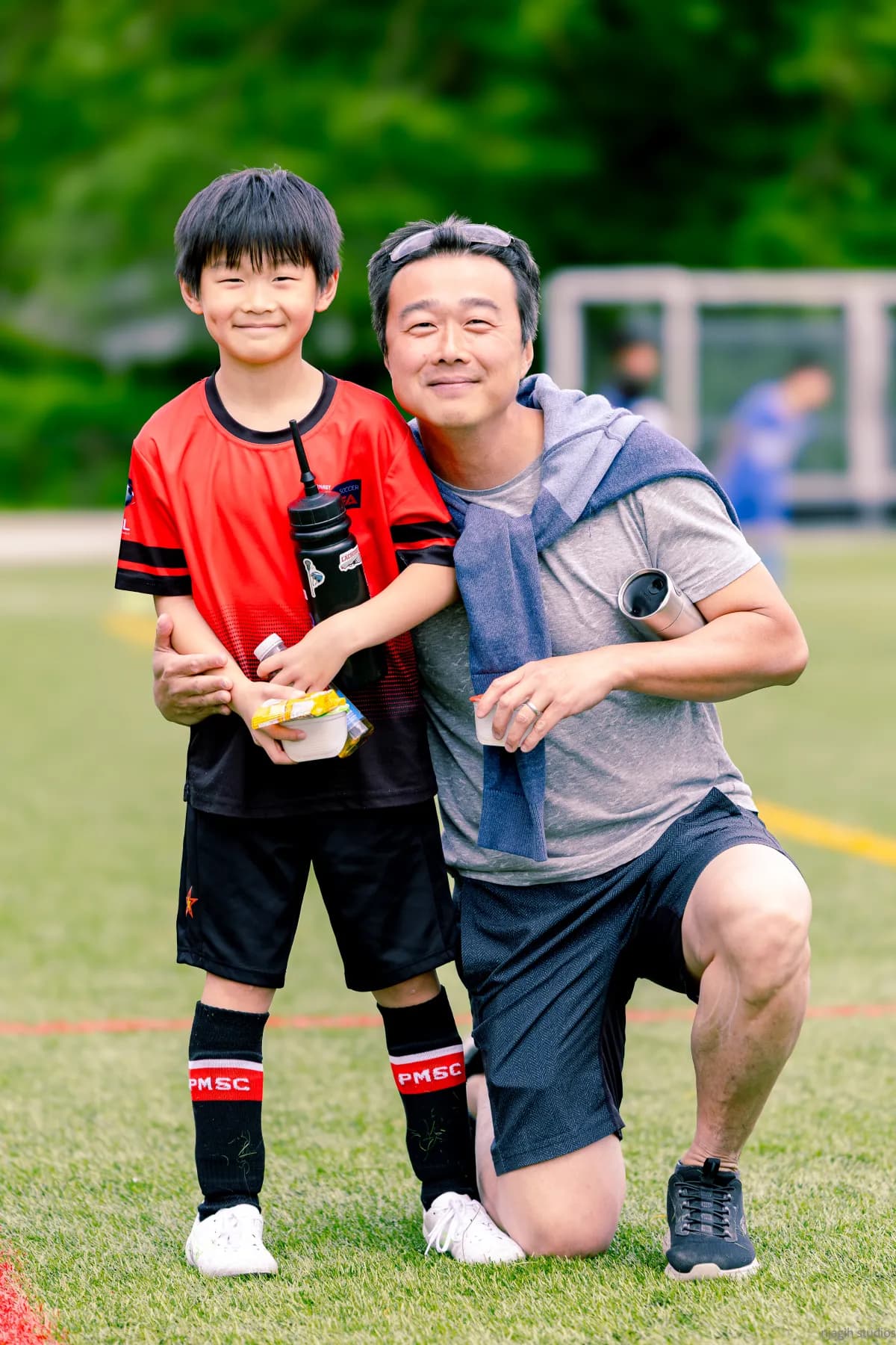 Father and son posing together at youth soccer field after game - Njagih Studios sports portrait photography
