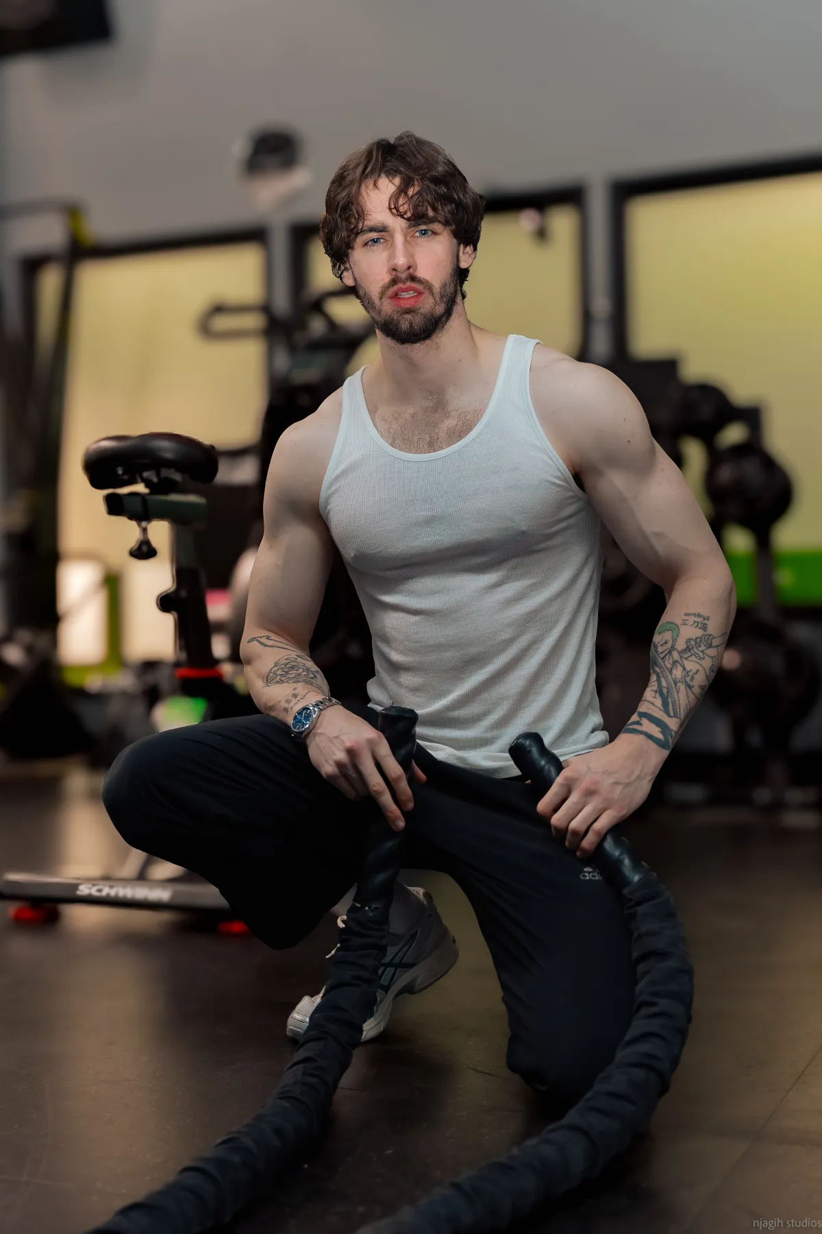Fitness athlete seated with battle ropes in gym portrait session - Njagih Studios fitness photography