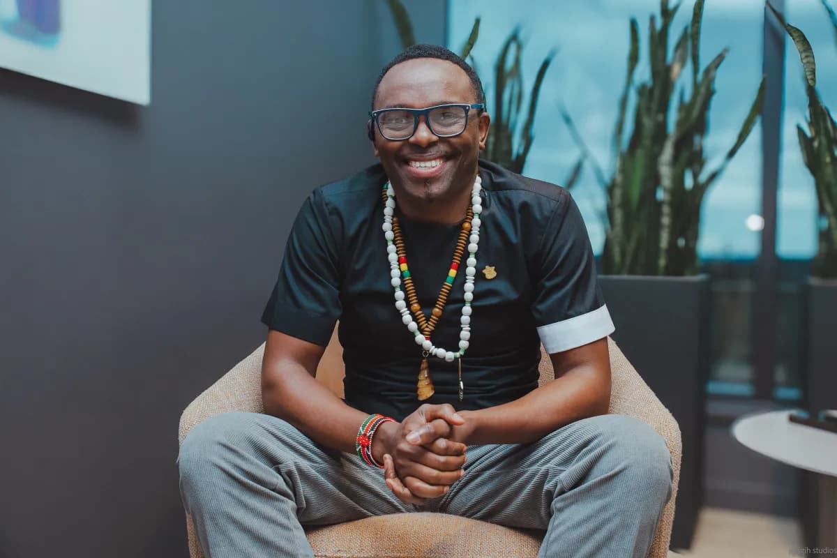 Man seated in lounge chair smiling for corporate portrait with beaded necklace - Njagih Studios portrait photography