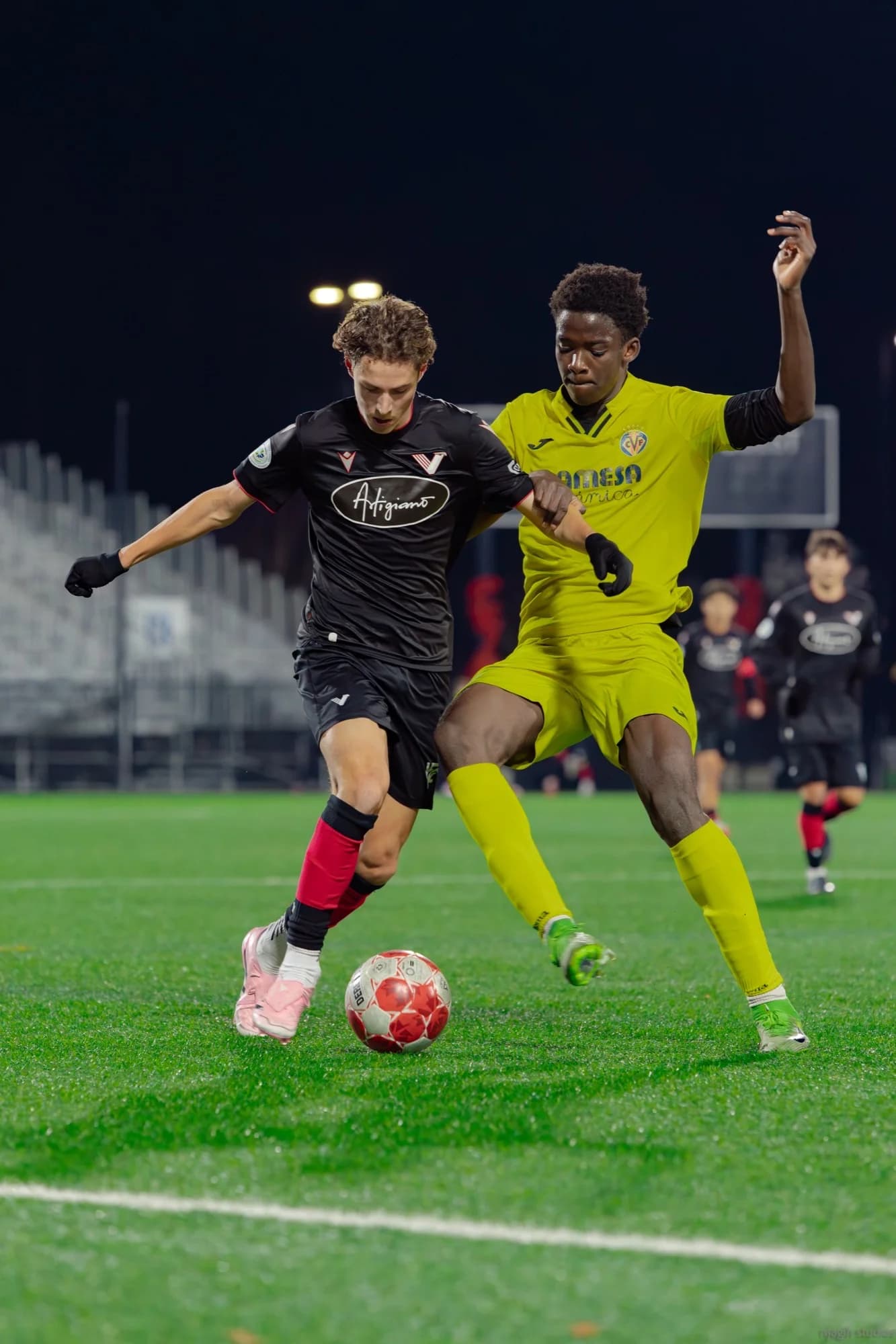 Intense night soccer duel between players challenging for the ball - Njagih Studios sports photography Vancouver