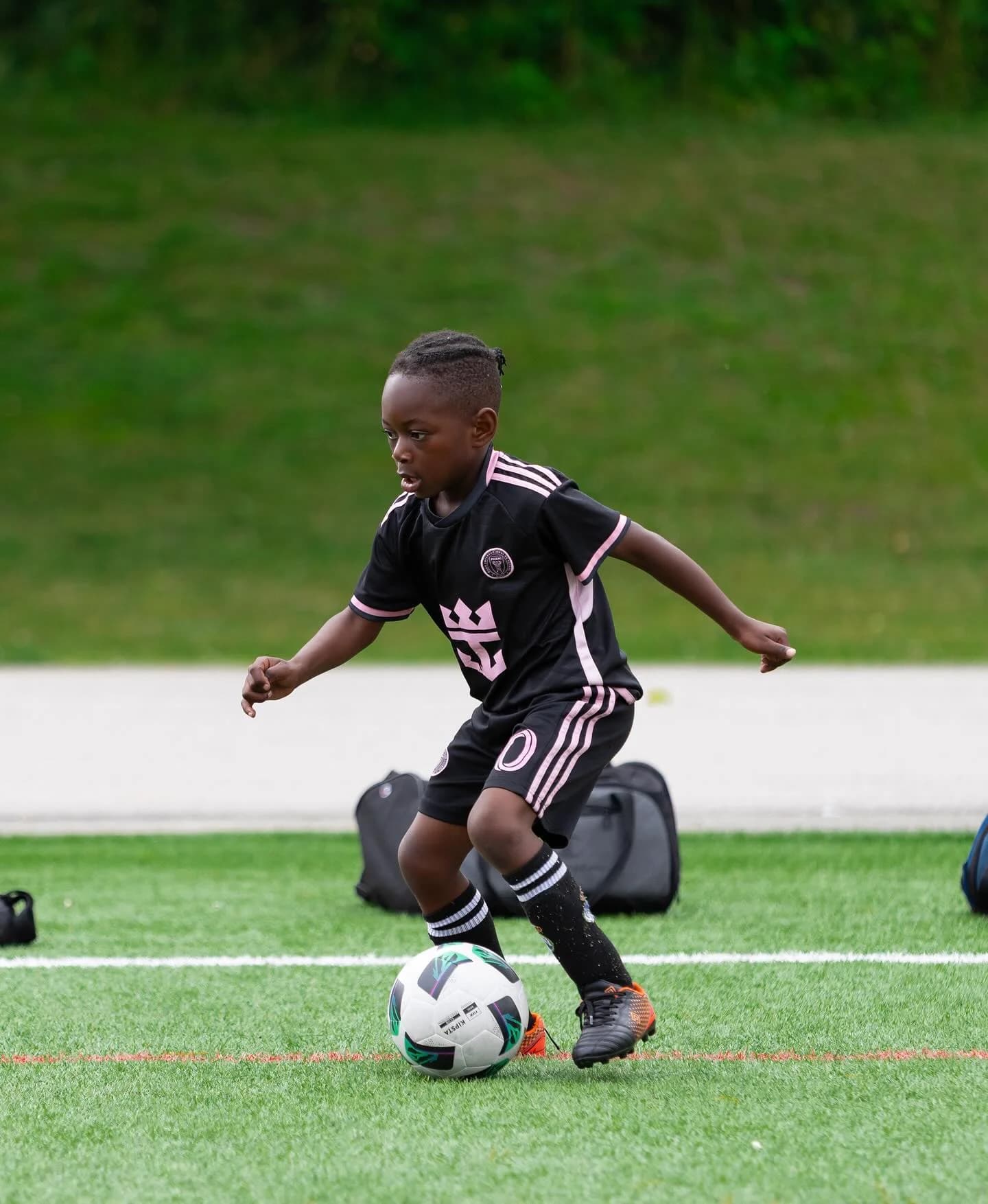 Young kid dribbling soccer ball on turf field in Vancouver - Njagih Studios youth sports photography