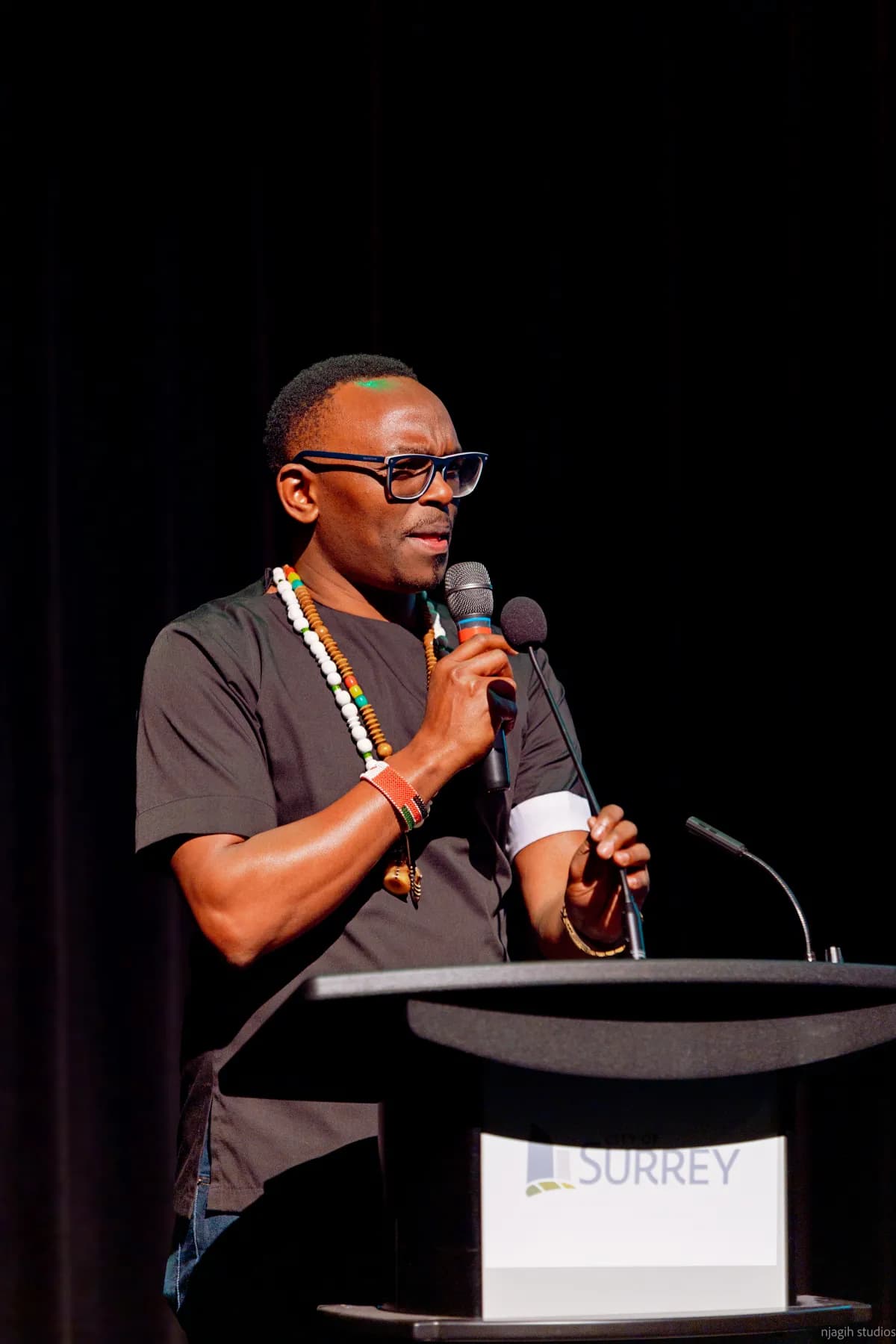 Keynote speaker presenting at podium during Surrey community event - Njagih Studios event photography