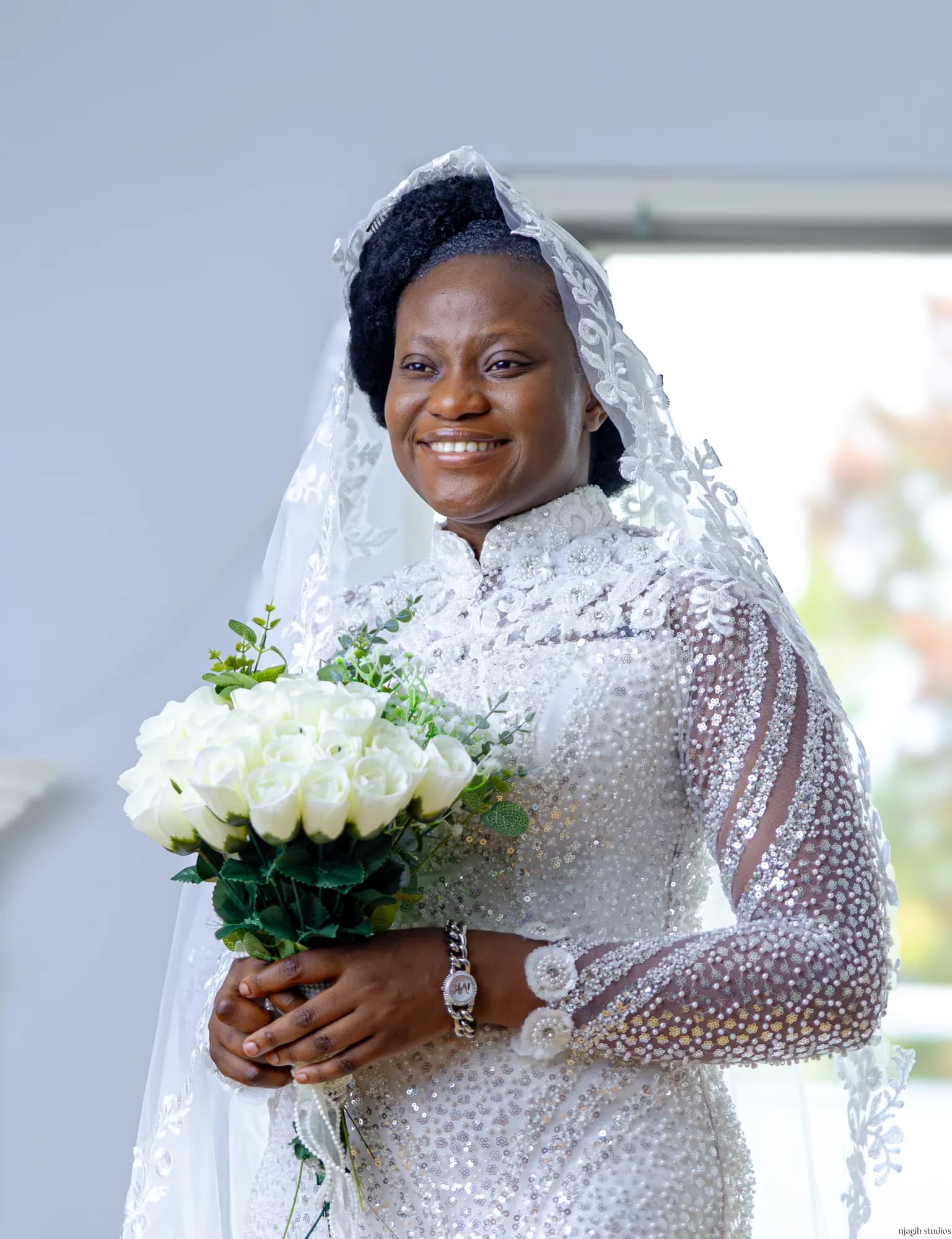 Bride portrait in beaded lace gown and veil holding white rose bouquet - Njagih Studios wedding photography