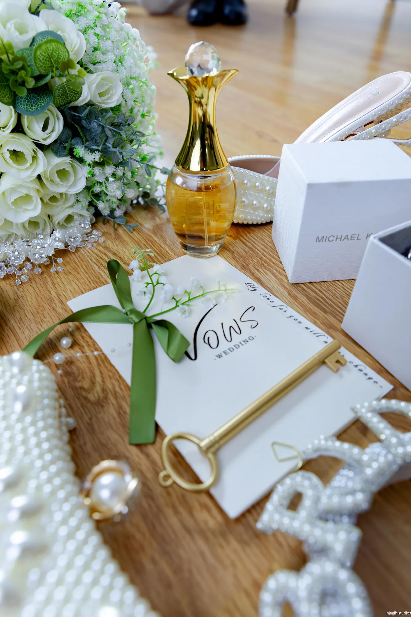 Wedding vows booklet with bridal bouquet perfume and gold jewelry details - Njagih Studios wedding photography