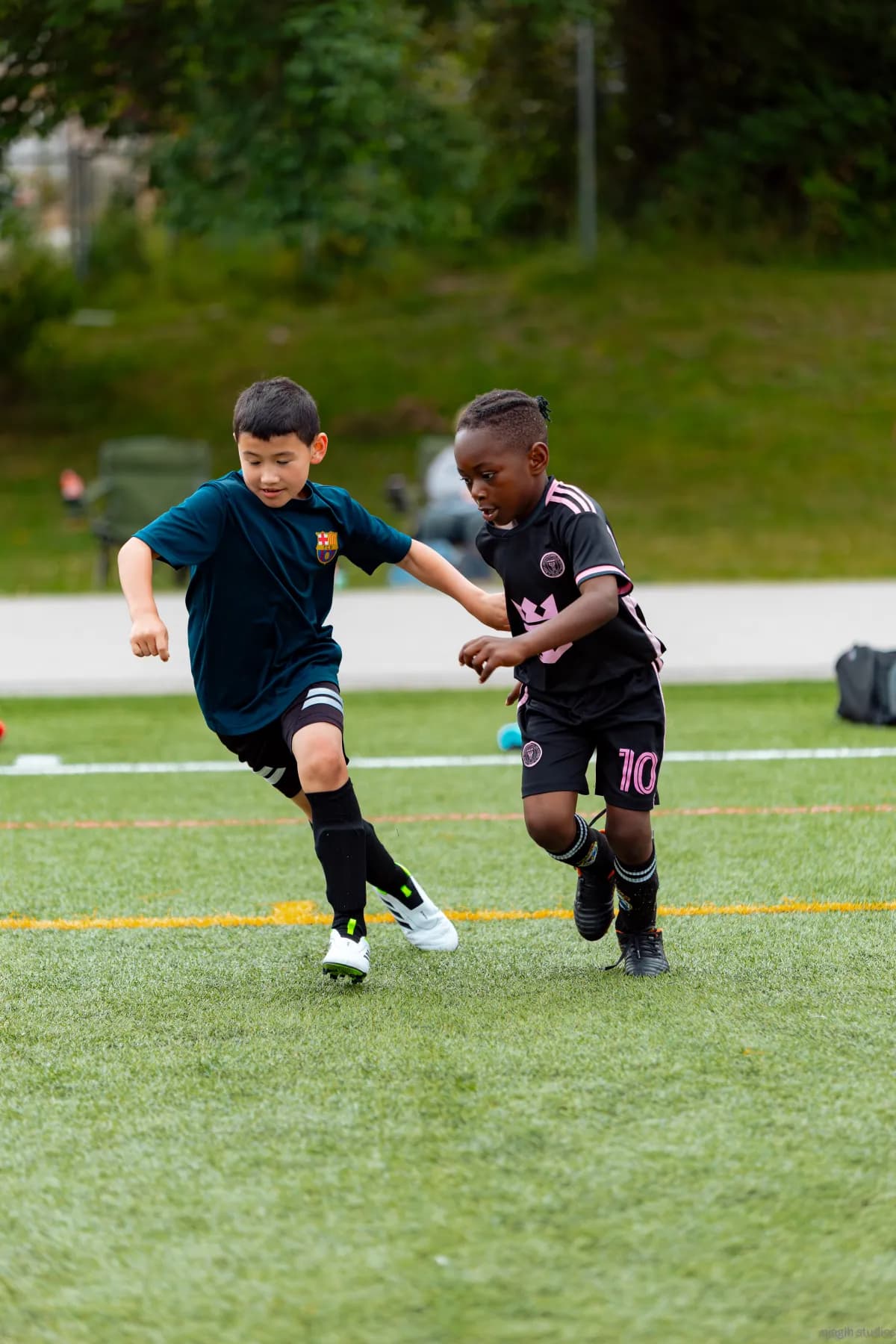 Two youth soccer players battling for possession during outdoor match - Njagih Studios sports photography