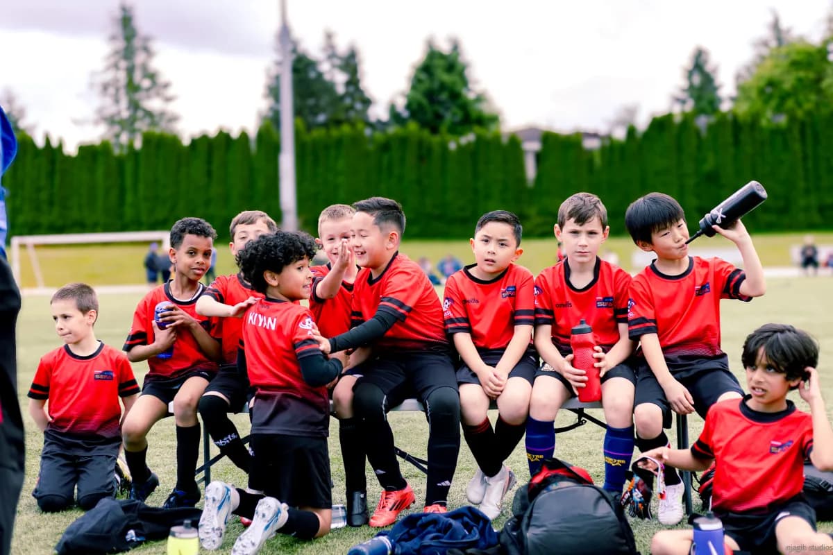 Youth soccer team sitting together on bench during halftime break - Njagih Studios sports photography